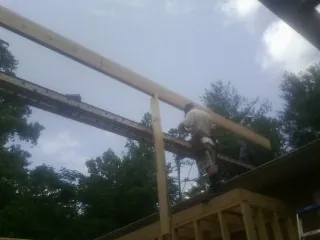 Carpenter setting a ridge beam over a new addition frame — Ice Dam Removal by Roofing Brothers in Westerlo