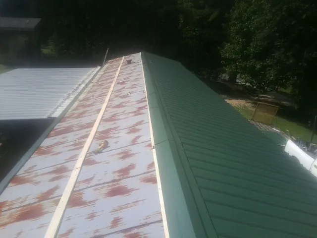Old rusted panels beside newly installed green metal roofing — Wind Damage Roof Repair by Roofing Brothers in Westerlo