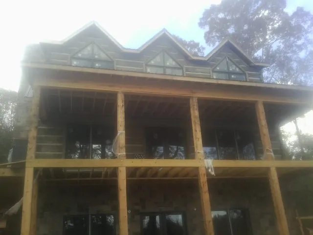 Dormers and porch framing on a large log home under construction — Roof Coating work by our crew in Westerlo