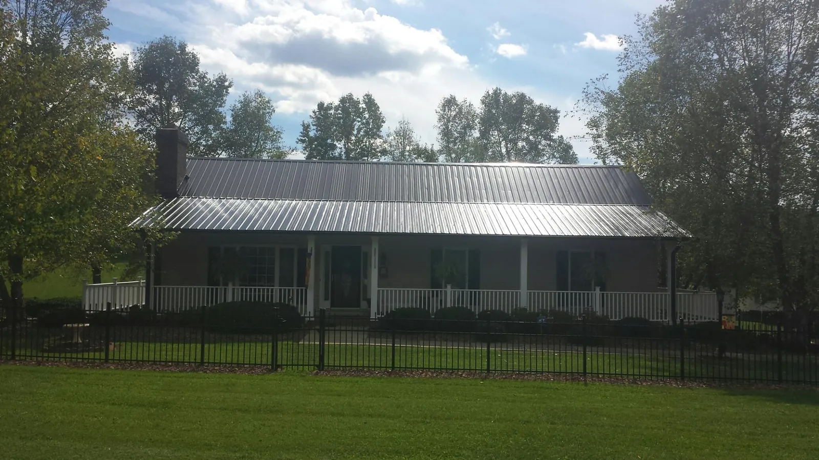 Gray metal roof on a brick ranch with a full width front porch — Gutter Guard Installation work by our crew in Westerlo