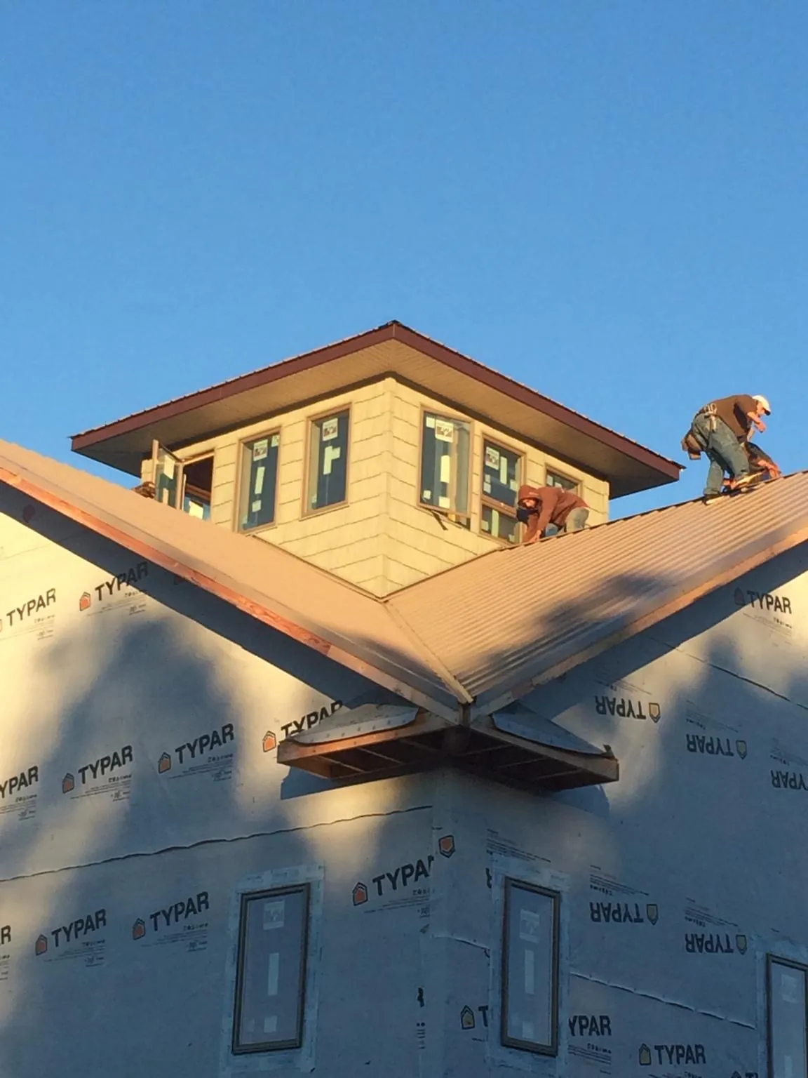 Roofers working around a rooftop cupola on a new metal roof at sunset — Roof Waterproofing in Westerlo by Roofing Brothers